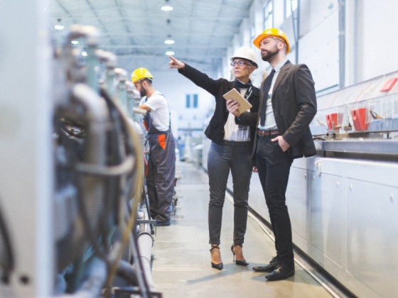 Two professionals in hard hats review industrial equipment.