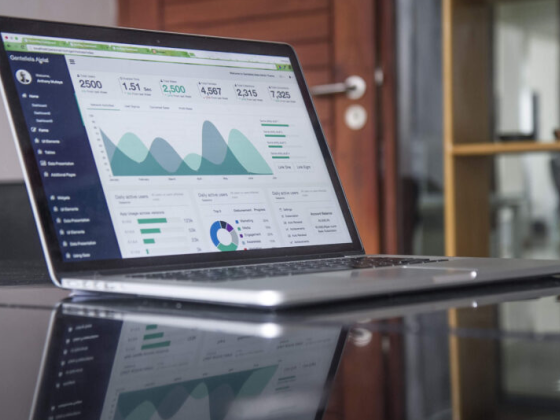 A sleek laptop shows various data graphs and metrics.