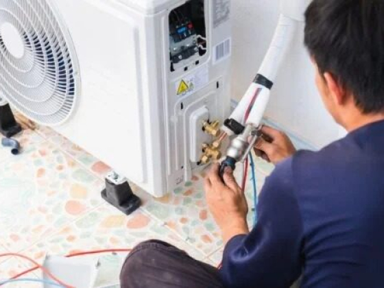 A technician repairs an air conditioning unit indoors.