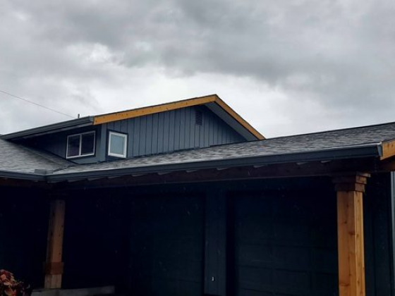 A modern gray house with wooden accents on a cloudy day