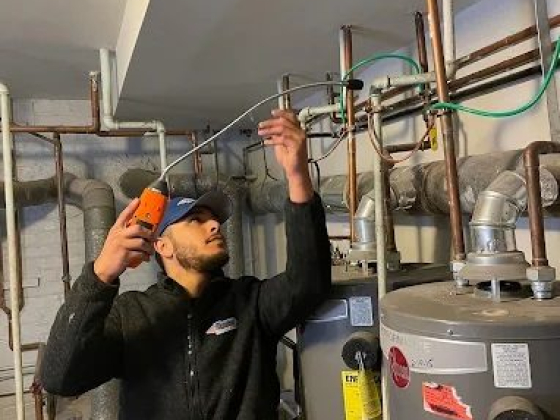 Technician inspecting water heater pipes