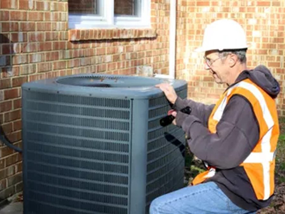 Worker checks air conditioning unit outside brick building