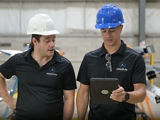 Two workers in hard hats reviewing tablet data in an industrial setting