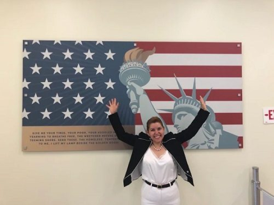Smiling person raises arms in front of USA flag mural