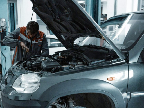 Mechanic repairs vehicle under open hood