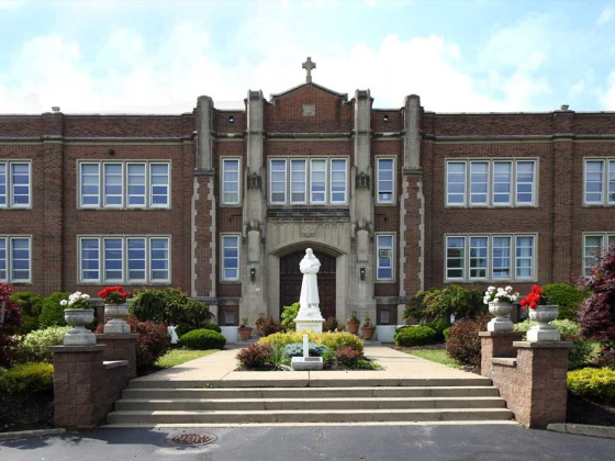 Classic brick school building with pathway and sculpture