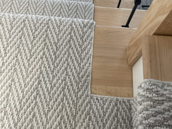 A staircase with a textured gray carpet runner