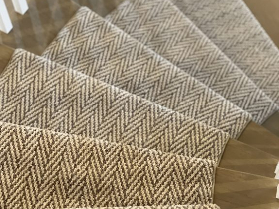 Stairs featuring a beige herringbone carpet design