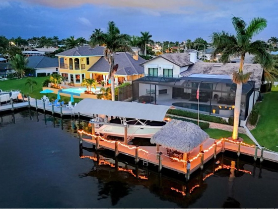 Elegant estate with pool and boat dock at sunset