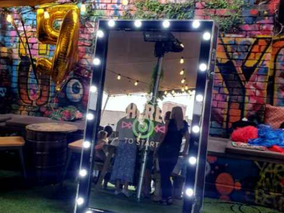 Photo booth mirror surrounded by lights at a party