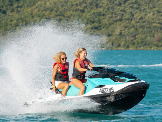Smiling duo enjoying a jet ski ride across clear waters