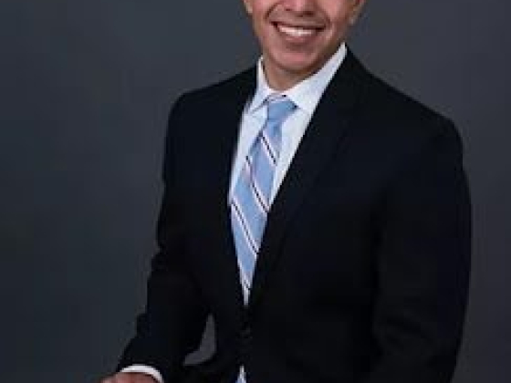 Man posed formally against a dark background