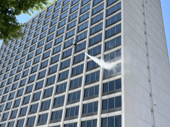 A drone sprays water on a high-rise building.