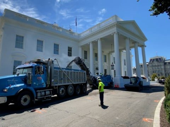 A truck and worker near a grand white structure.
