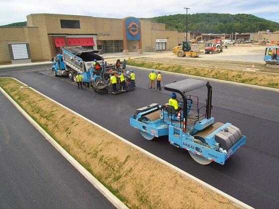 Workers and machinery at a construction site paving asphalt