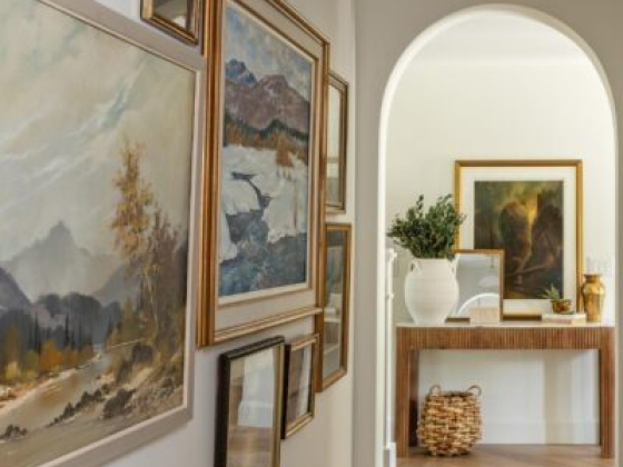 Hallway with framed art leading to room through archway