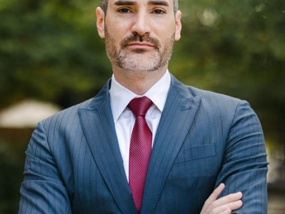 Confident man in blue suit and red tie crossing arms