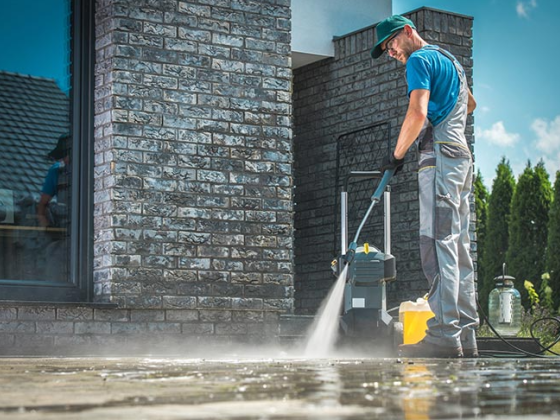 Worker cleaning outdoor pavement using pressure washer