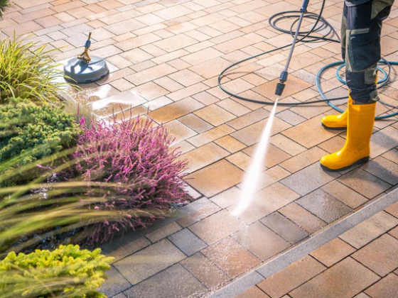 Cleaning patio tiles with a pressure washer and yellow boots