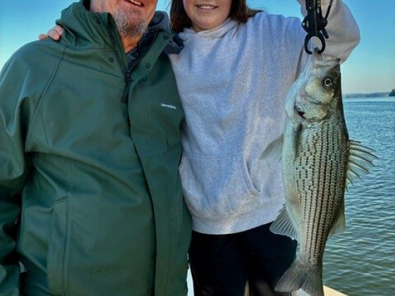 Father and daughter fishing success with striped bass catch