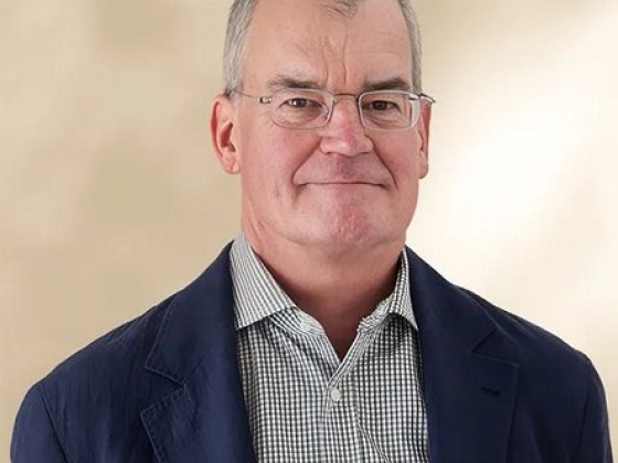 Middle-aged man wearing glasses and a suit jacket