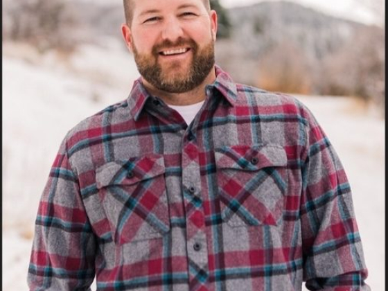 Smiling man in plaid shirt with snowy landscape background