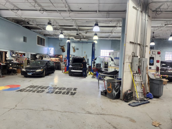 Busy auto body shop with cars and repair equipment