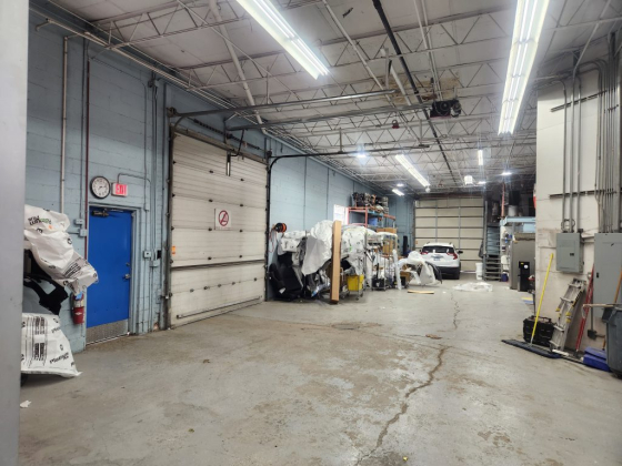 Interior of a large garage with equipment and a parked car