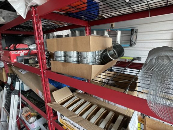 Red metal shelving unit holding various boxes and equipment