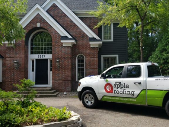 Apple Roofing truck parked in front of a brick house