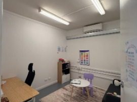 Office with a desk, chairs, and colorful wall posters.