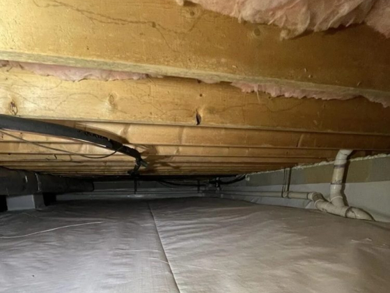 Crawl space lined with insulation and PVC piping