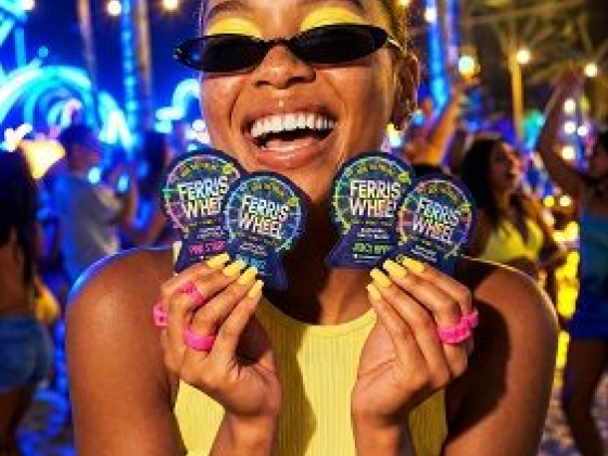 Smiling woman holding Ferris Wheel event passes at beach party