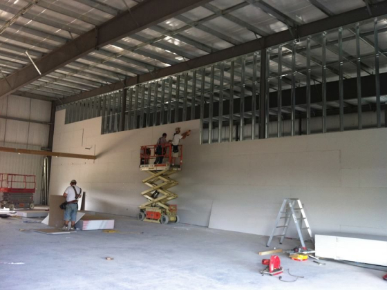 Workers on lift fixing wall panels in a warehouse
