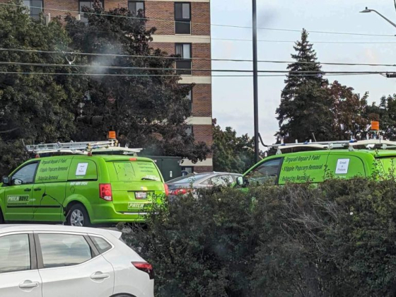 Green vans used for repair services parked by road