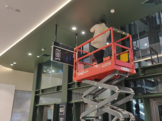 Maintenance worker on lift in a building lobby