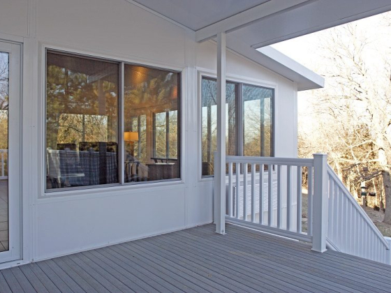 Sunny porch with white railings and large glass windows
