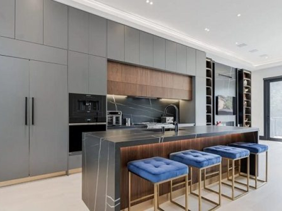 Sleek kitchen featuring island with blue stools and built-in appliances