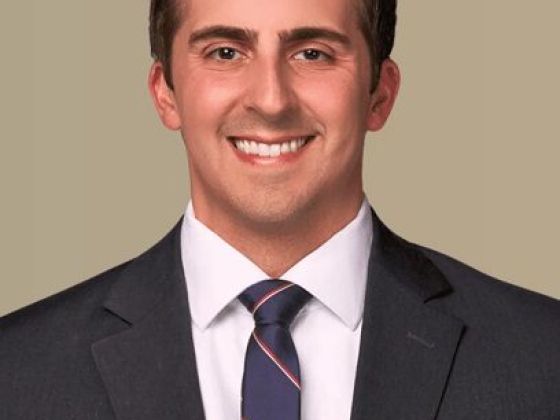 Young man in formal attire against a plain background