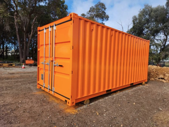 An orange container sits on dirt near trees