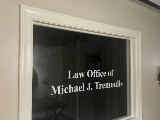 Sign for Michael J. Tremoulis' law office on a glass window.
