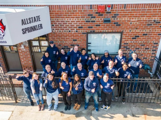 Team posing in matching uniforms outside office