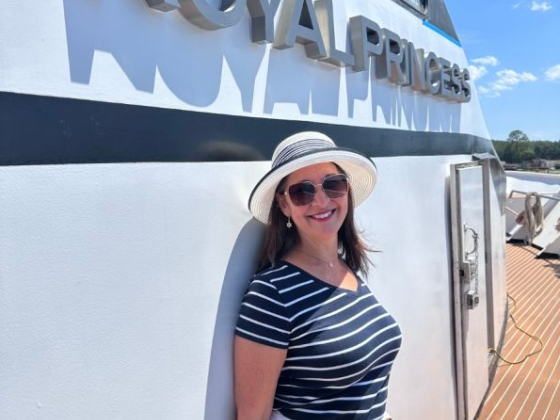 Woman in hat and sunglasses leaning against boat