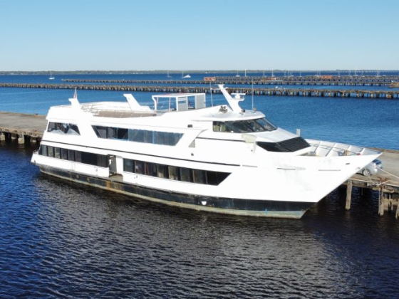 A large white yacht moored at a wooden pier