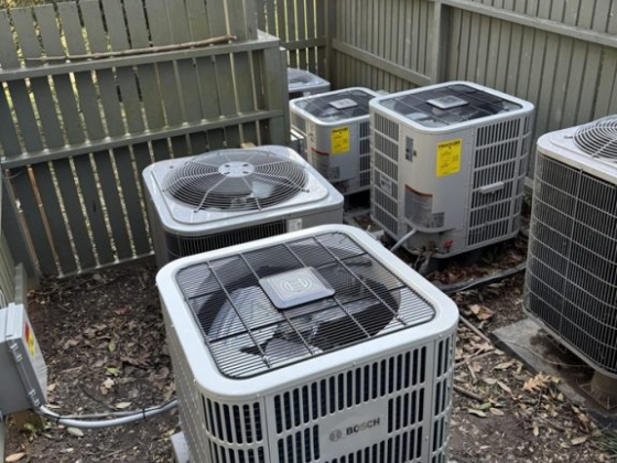 Multiple AC units in a fenced area outdoors