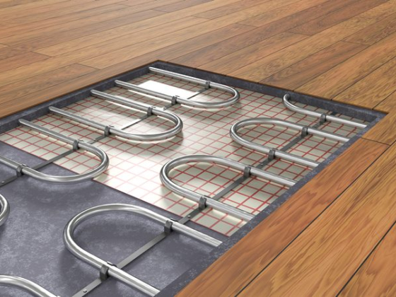 Underfloor heating pipes beneath wood flooring section