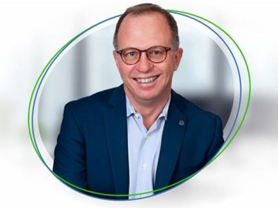 Man in blue suit and glasses smiling at camera