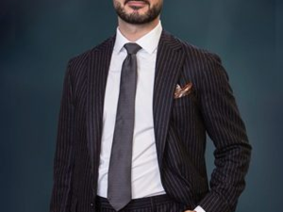 Stylish man posing in a pinstripe suit against blue backdrop