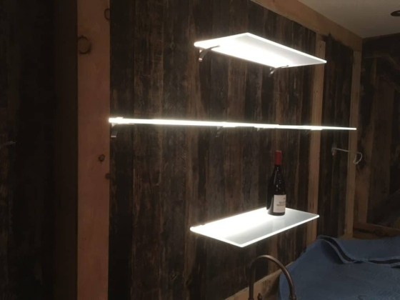 Wine bottle on illuminated wall shelves with rustic background