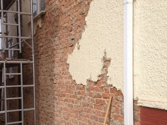 Exposed brick wall undergoing plastering repair
